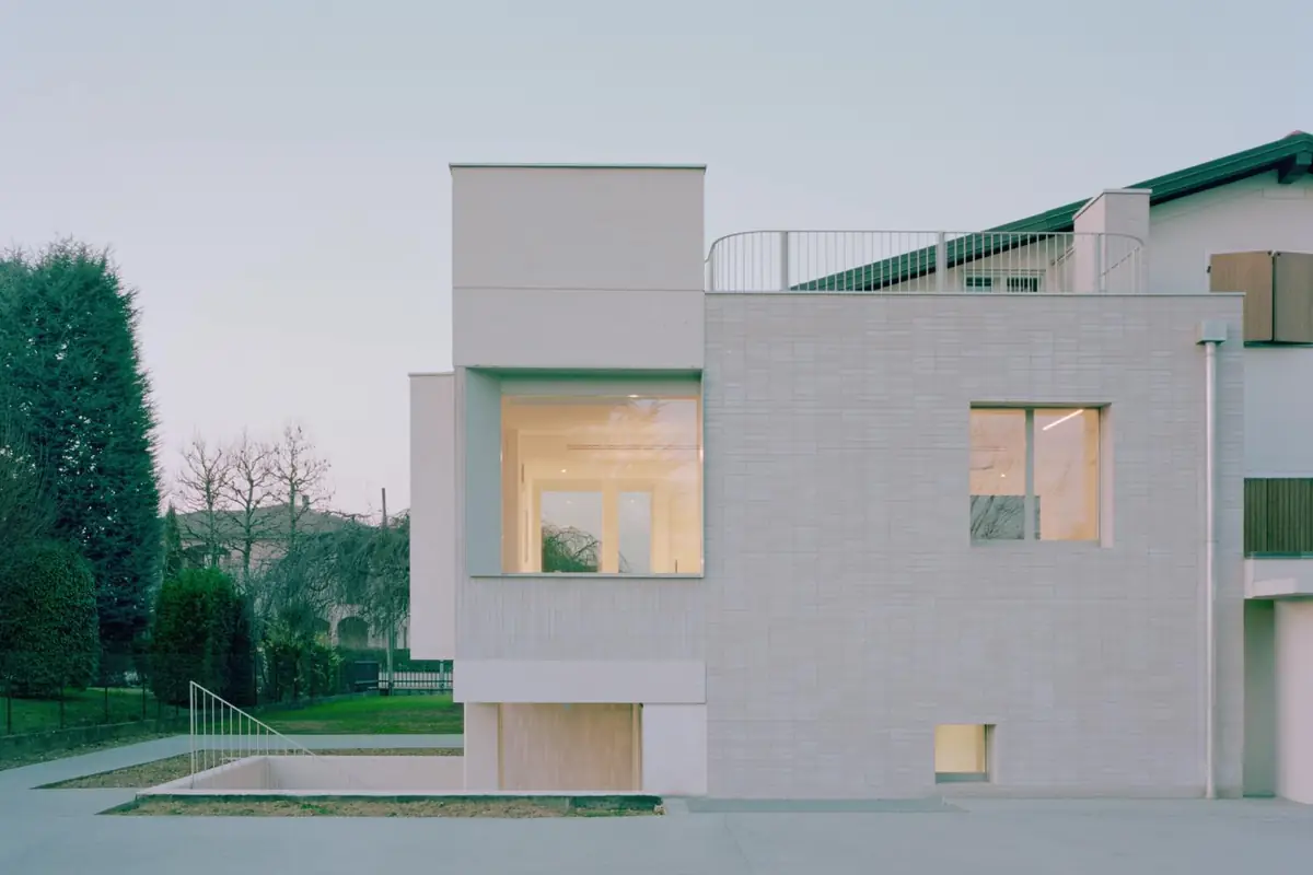 Detached house with a façade clad in elongated white compacted stone pieces