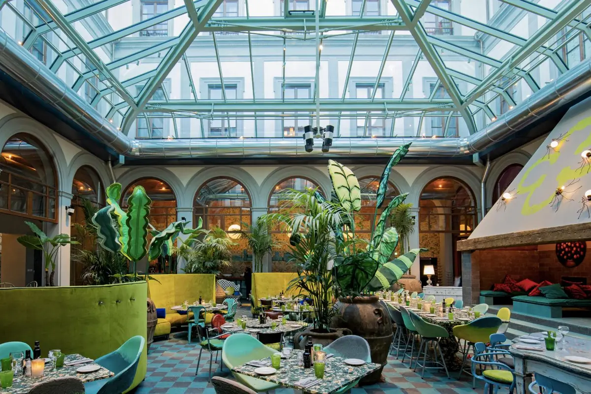 Covered hotel courtyard with a restaurant and a chequered compacted stone floor in greens and blues