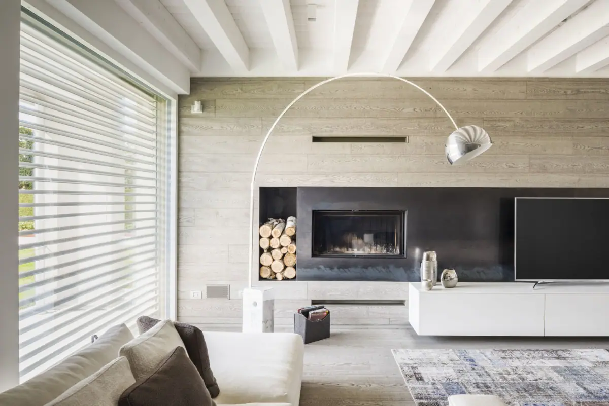 Living room with a wall clad in light oak boards, a fireplace set into a black surround and a wooden floor
