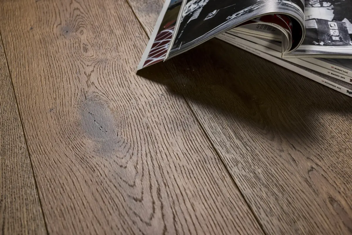 Wide boards of brushed greyish-brown oak with some magazines resting on the floor