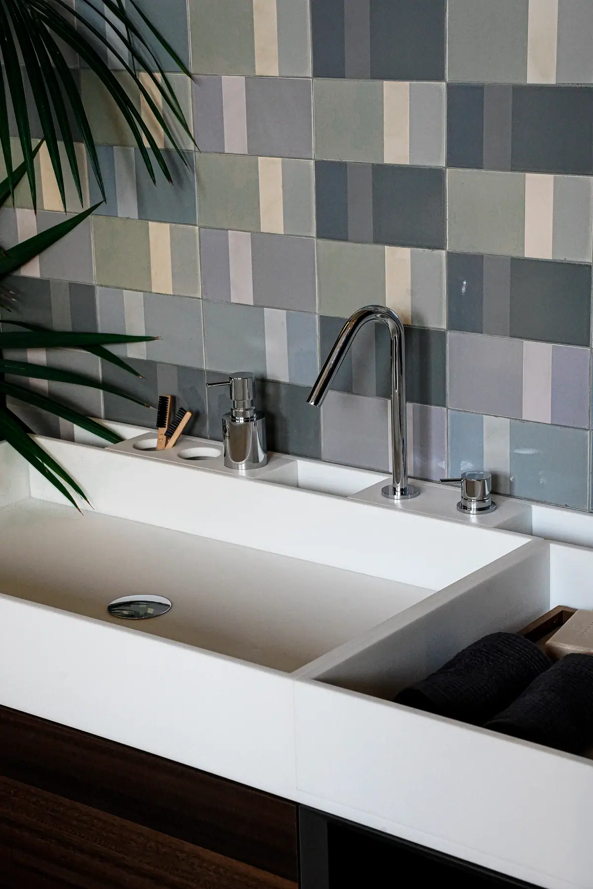 Detail of a white basin with a tall chrome spout, separate control and soap dispenser.