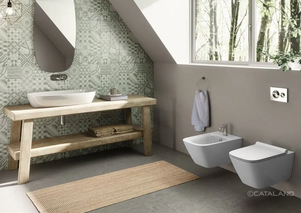 Attic bathroom with a white washbasin on a wooden bench, a wall of green encaustic tiles and a wall-hung WC and bidet