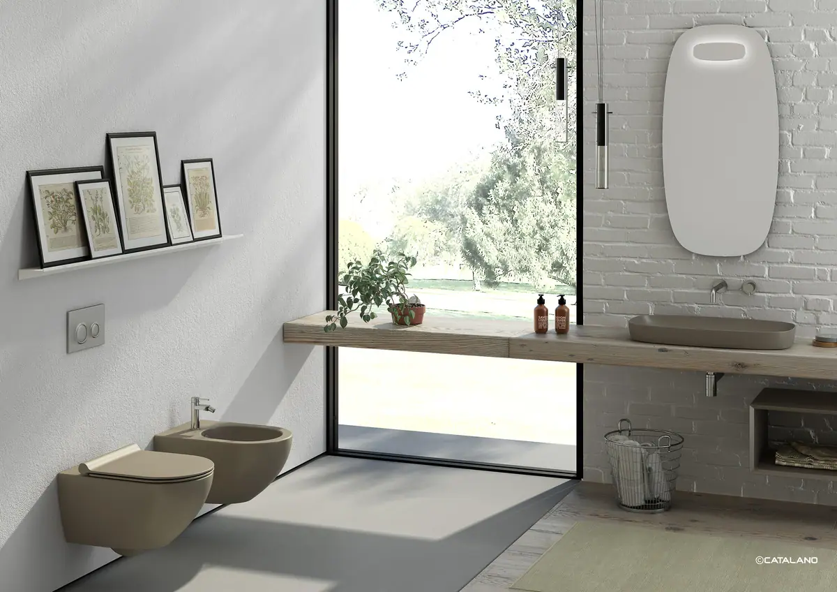 Bathroom with a satin brown washbasin on a wooden worktop by a window and a wall-hung WC and bidet in the same colour