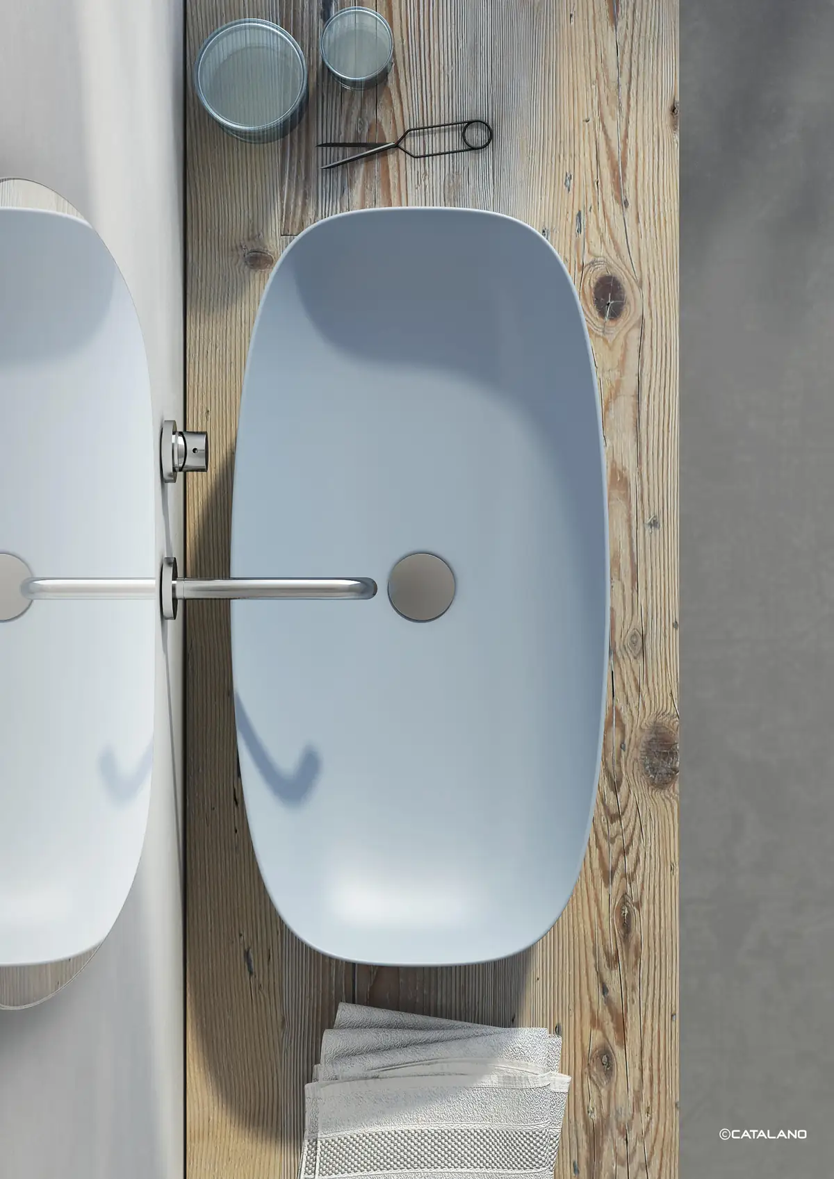 Overhead view of a blue washbasin with a wide bowl on a wooden worktop, with steel wall-mounted taps