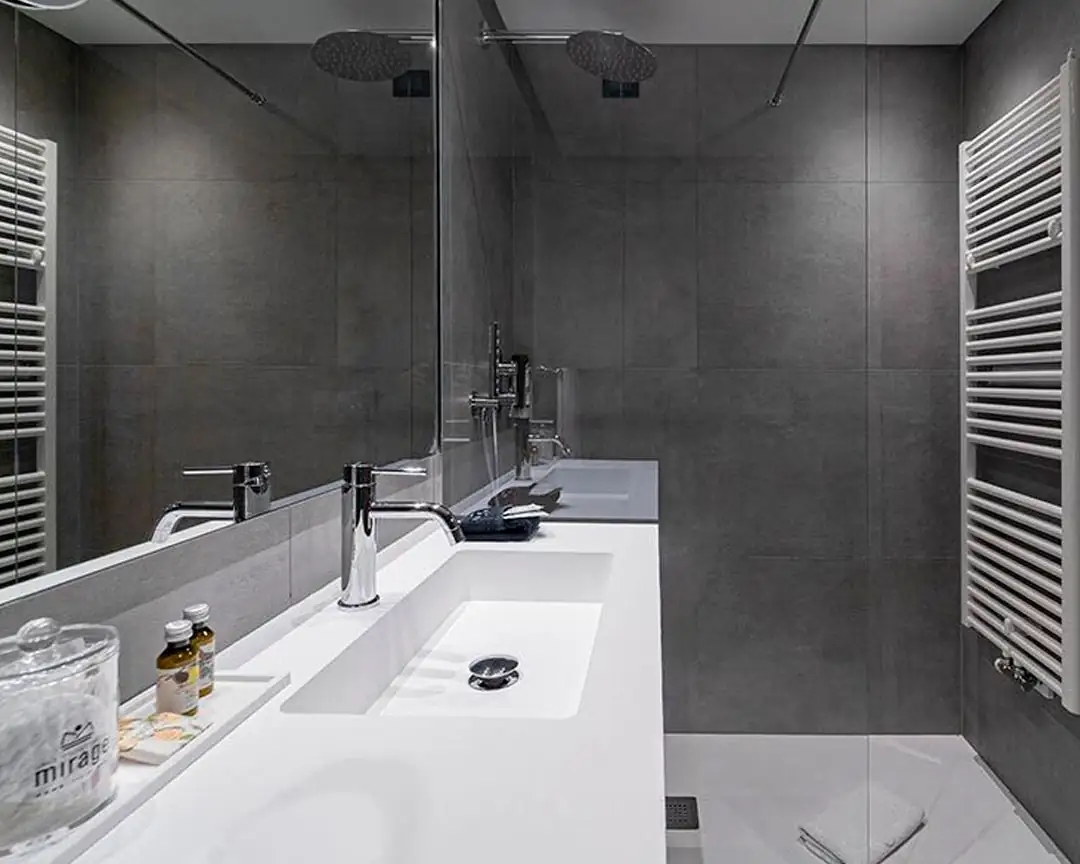 Bathroom with a white worktop with integrated washbasin, chrome taps, a mirror and dark grey porcelain stoneware walls