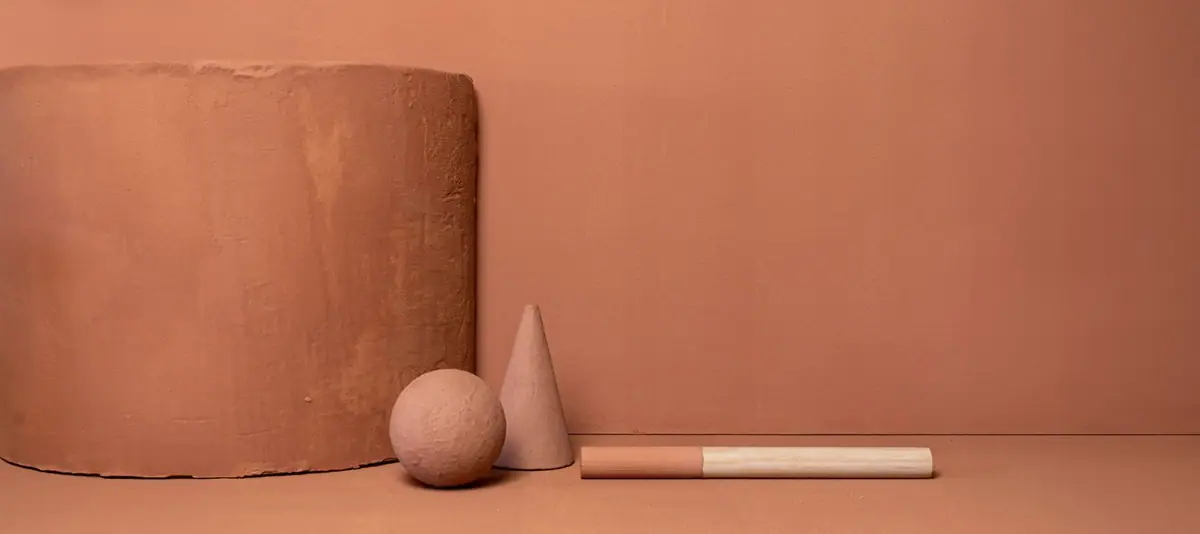Cylindrical block, sphere, cone and rod coated in terracotta on a background of the same colour