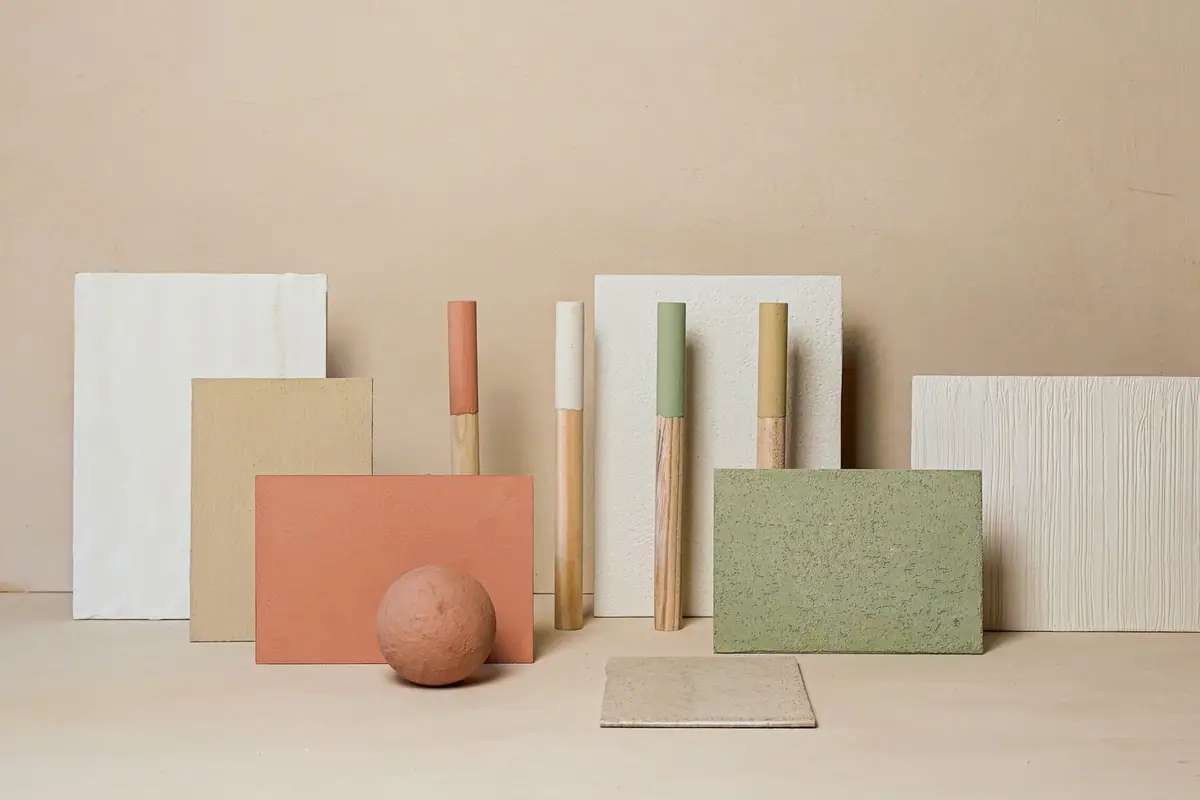 Samples of lime coatings in white, sand, terracotta and green alongside painted wooden rods and a textured sphere