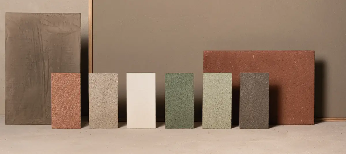 Rectangular lime coating samples in terracotta, sand, white, greens and dark grey against a painted background