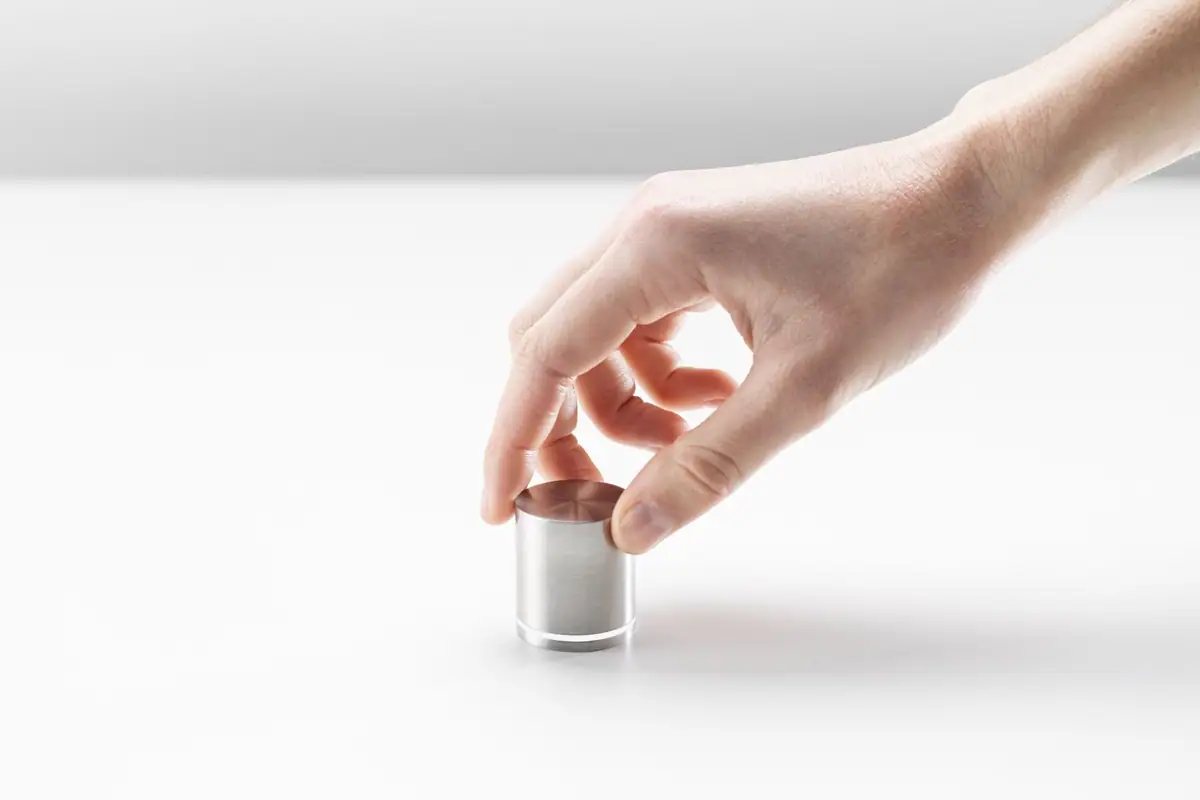 Hand turning a cylindrical stainless steel control on a white surface