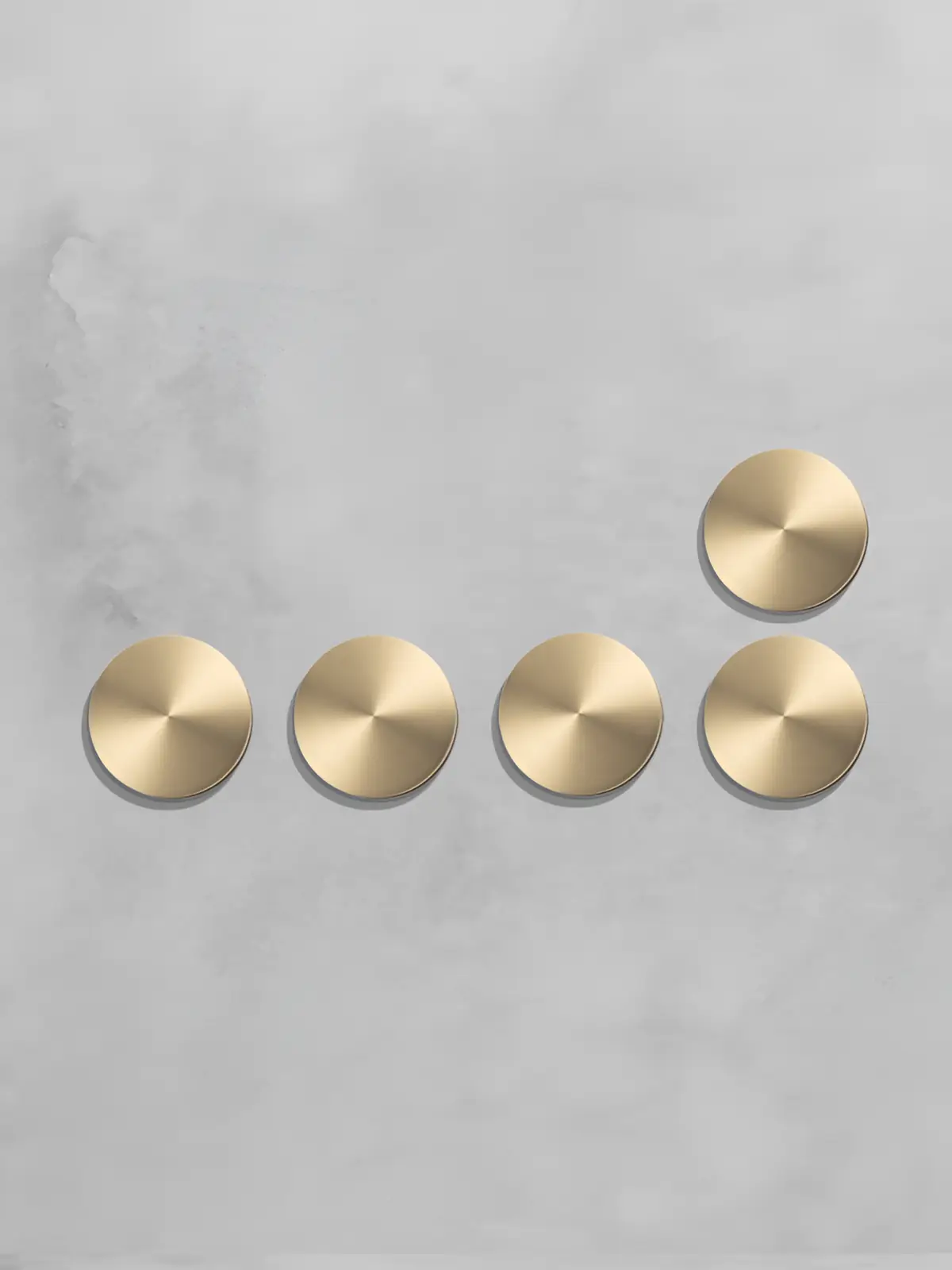Five gold circular controls arranged on a light grey wall