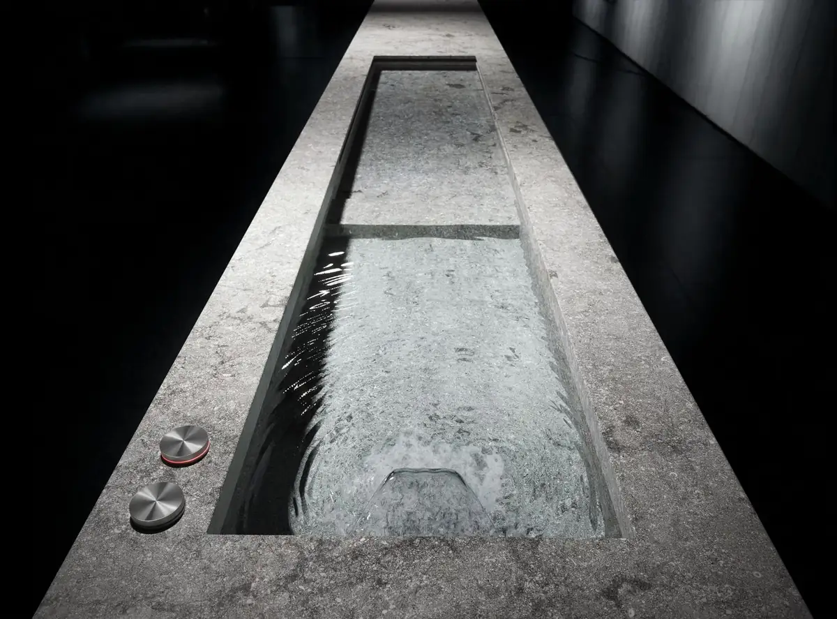 Long grey stone trough filled with water with two metal controls on its edge