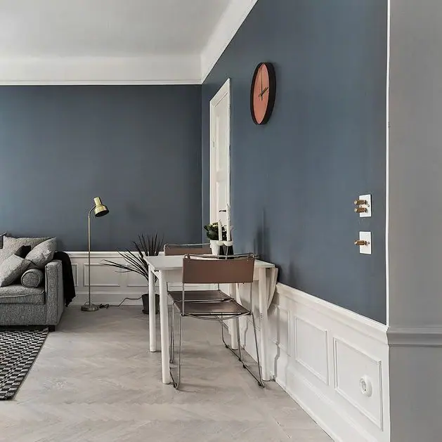 Living room with a blue wall, white moulded skirting and white-plate switches with brass knobs