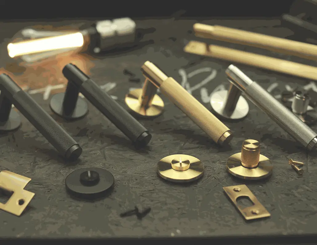 Door handles, pulls, knobs and door stops in brass, steel and black on a dark surface