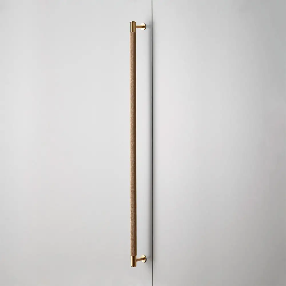 Long knurled brass pull handle on a white door