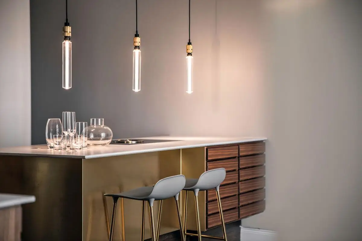 Three pendant lights with brass lampholders and elongated bulbs over a kitchen counter