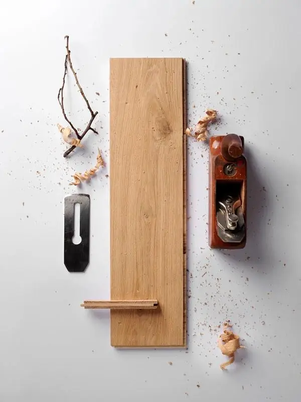 Hand-planed oak board next to a hand plane, its blade and shavings.