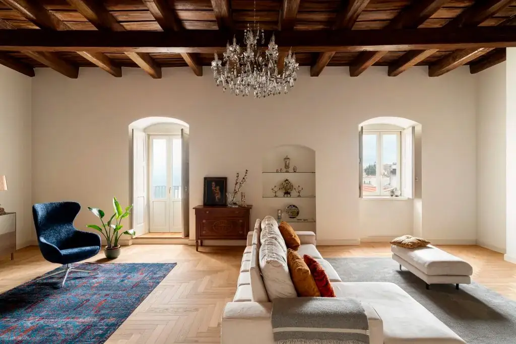 Living room with a timber-beamed ceiling, crystal chandelier and light oak herringbone floor.