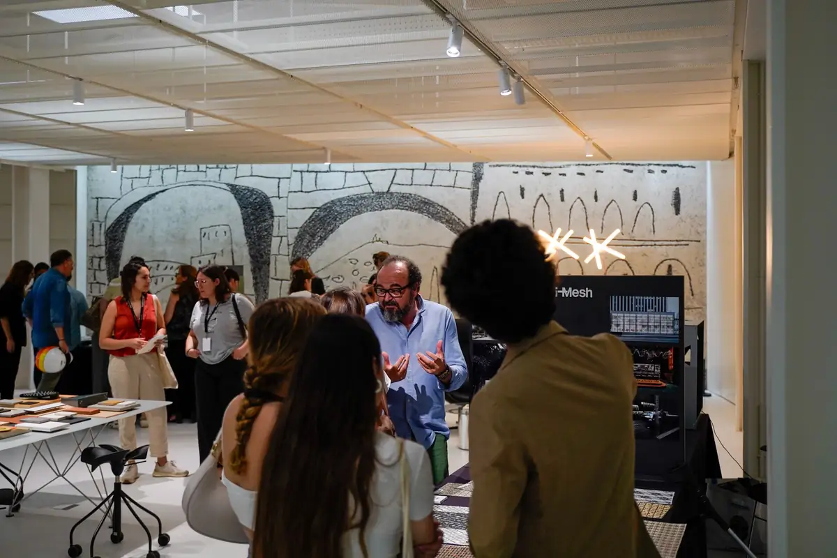 Visitantes conversando junto a la mesa de i-Mesh, con el friso de Picasso en la pared del fondo.