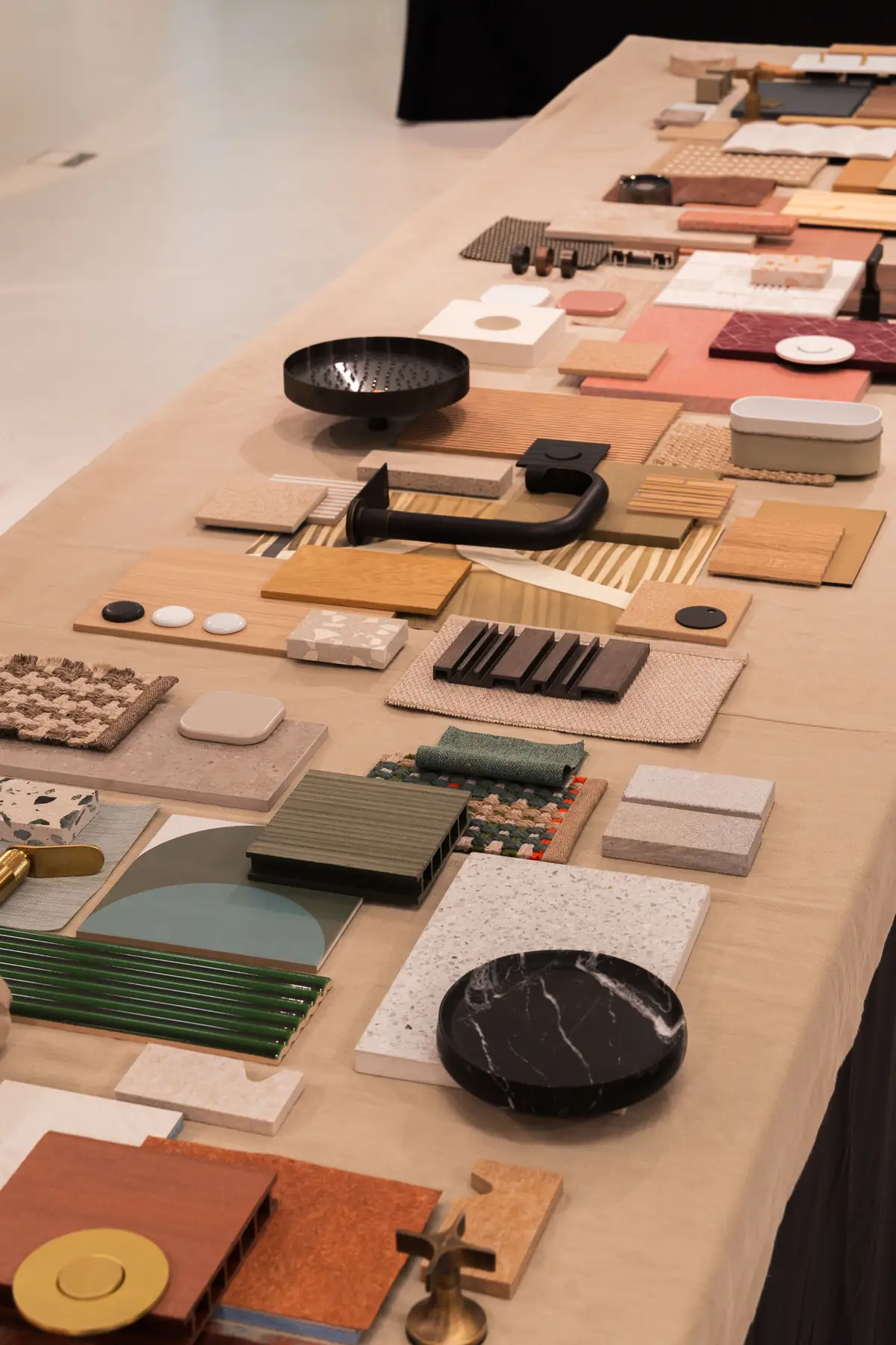 Mesa con muestras de cerámica, piedra, madera y metal dispuestas sobre un mantel claro.
