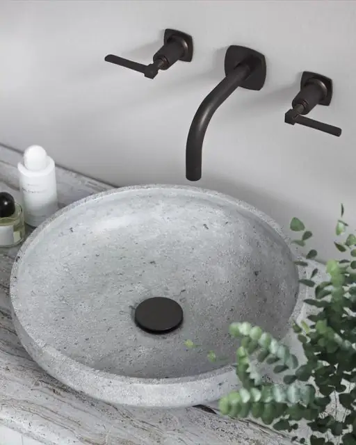 Grifo de lavabo mural negro con mandos de palanca sobre un lavabo de hormigón gris