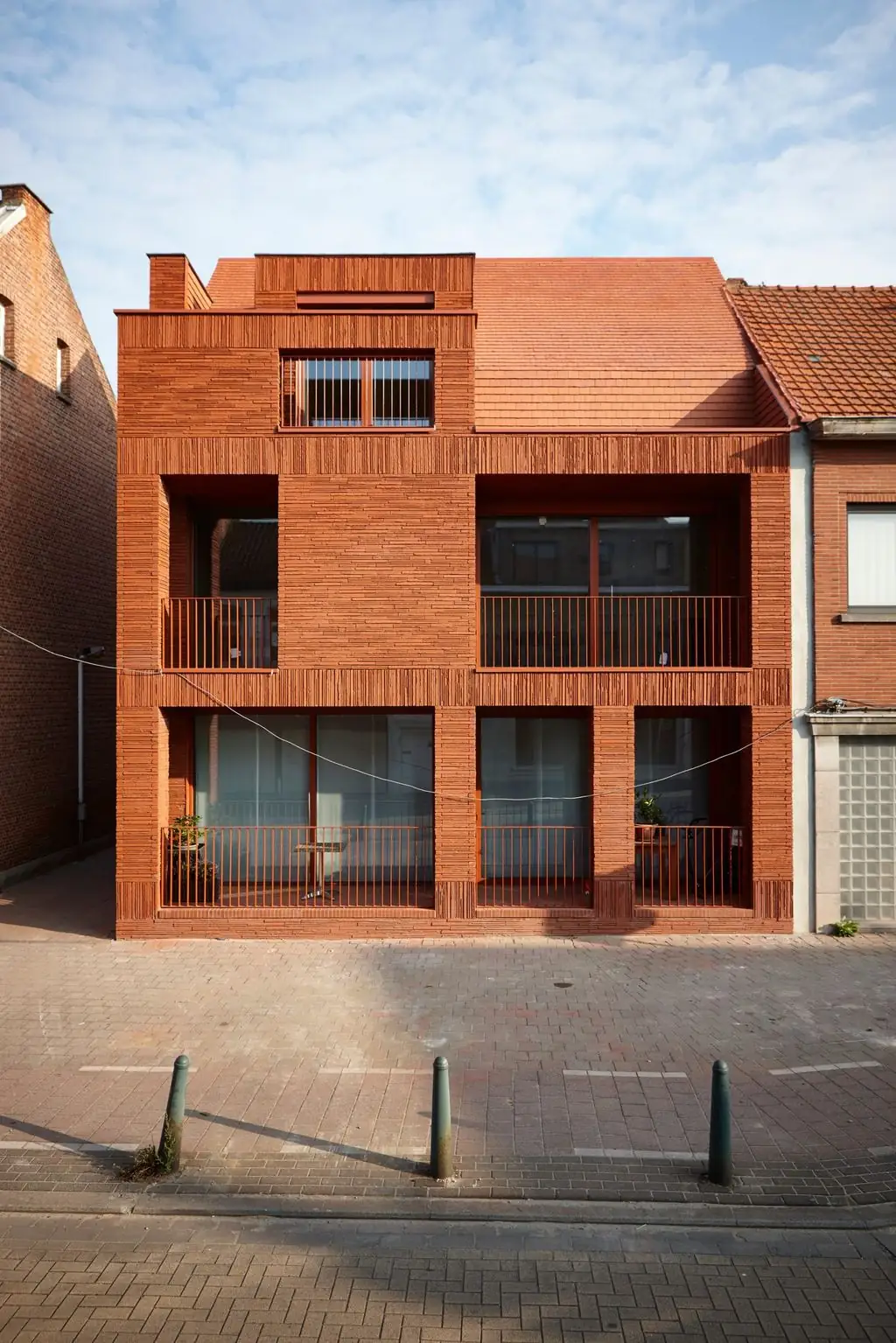Edificio de viviendas con fachada de ladrillo rojo largo y balcones con barandilla metálica