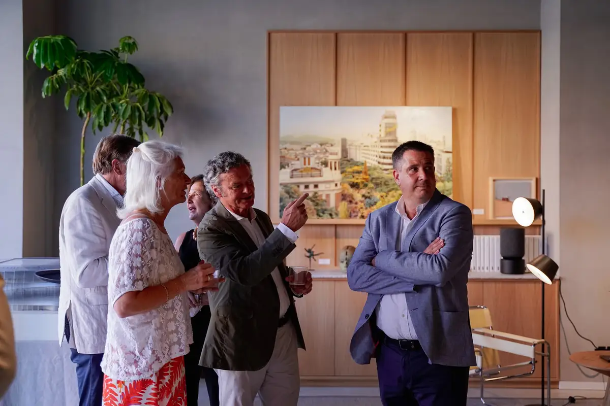 Guests talk in front of a painting of an urban view