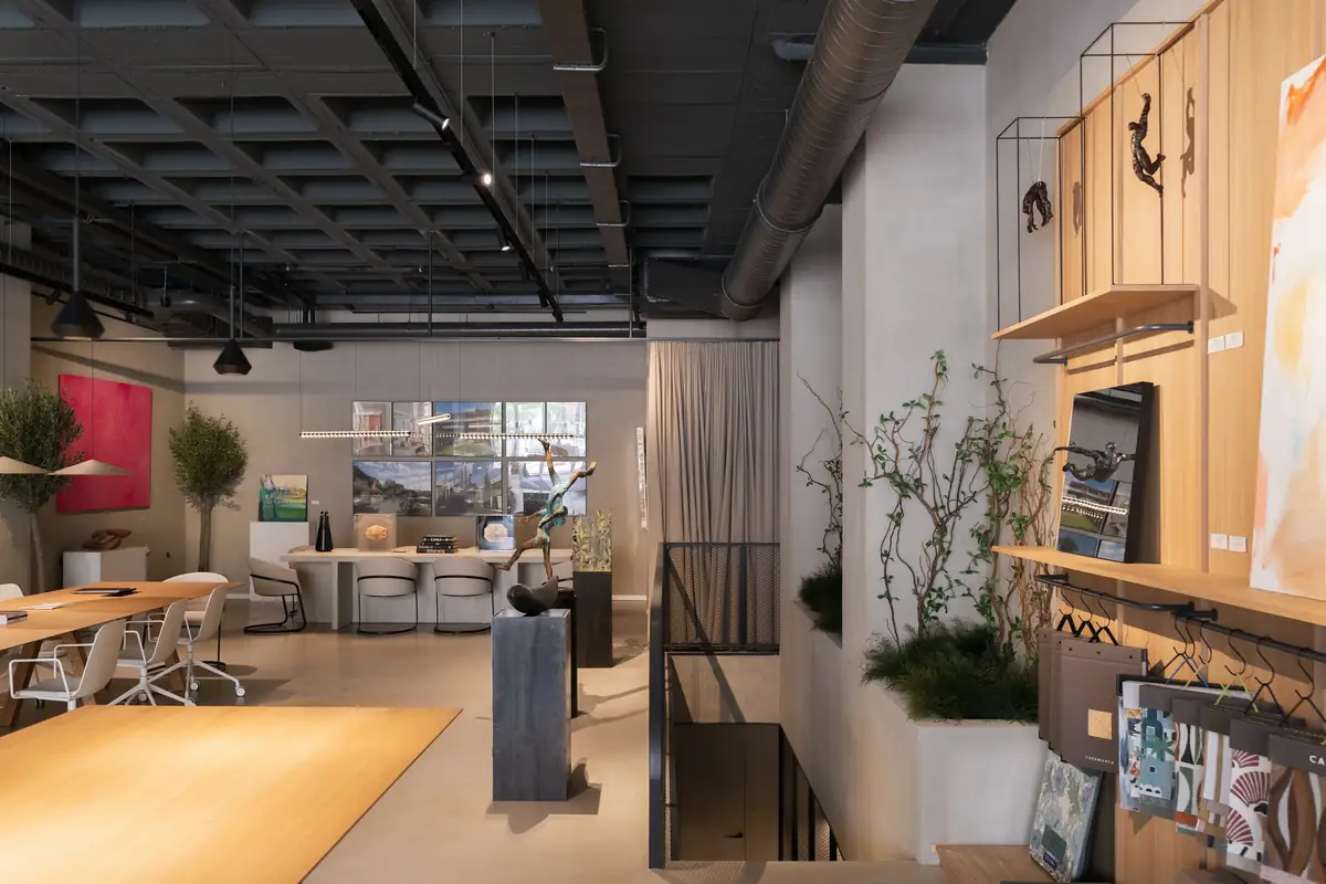 Work area with tables, plants and shelves with art pieces next to a staircase