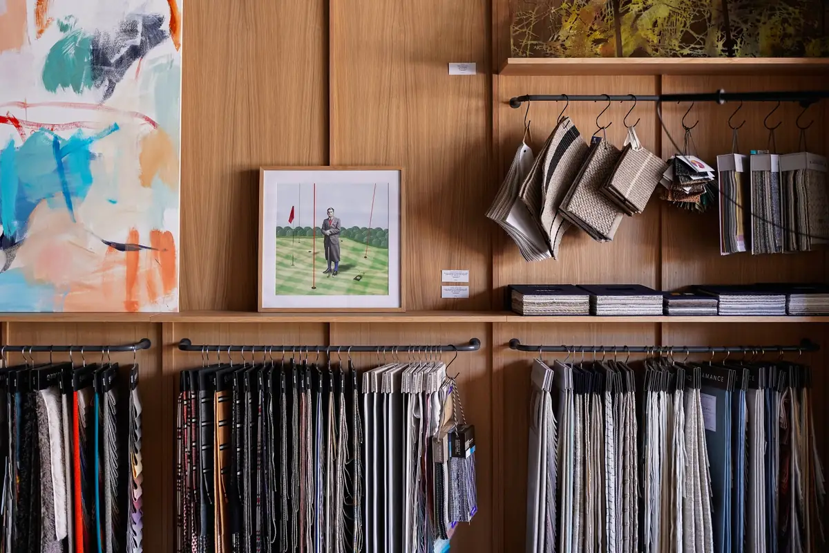 Textile swatches hanging beneath shelves with paintings and catalogues