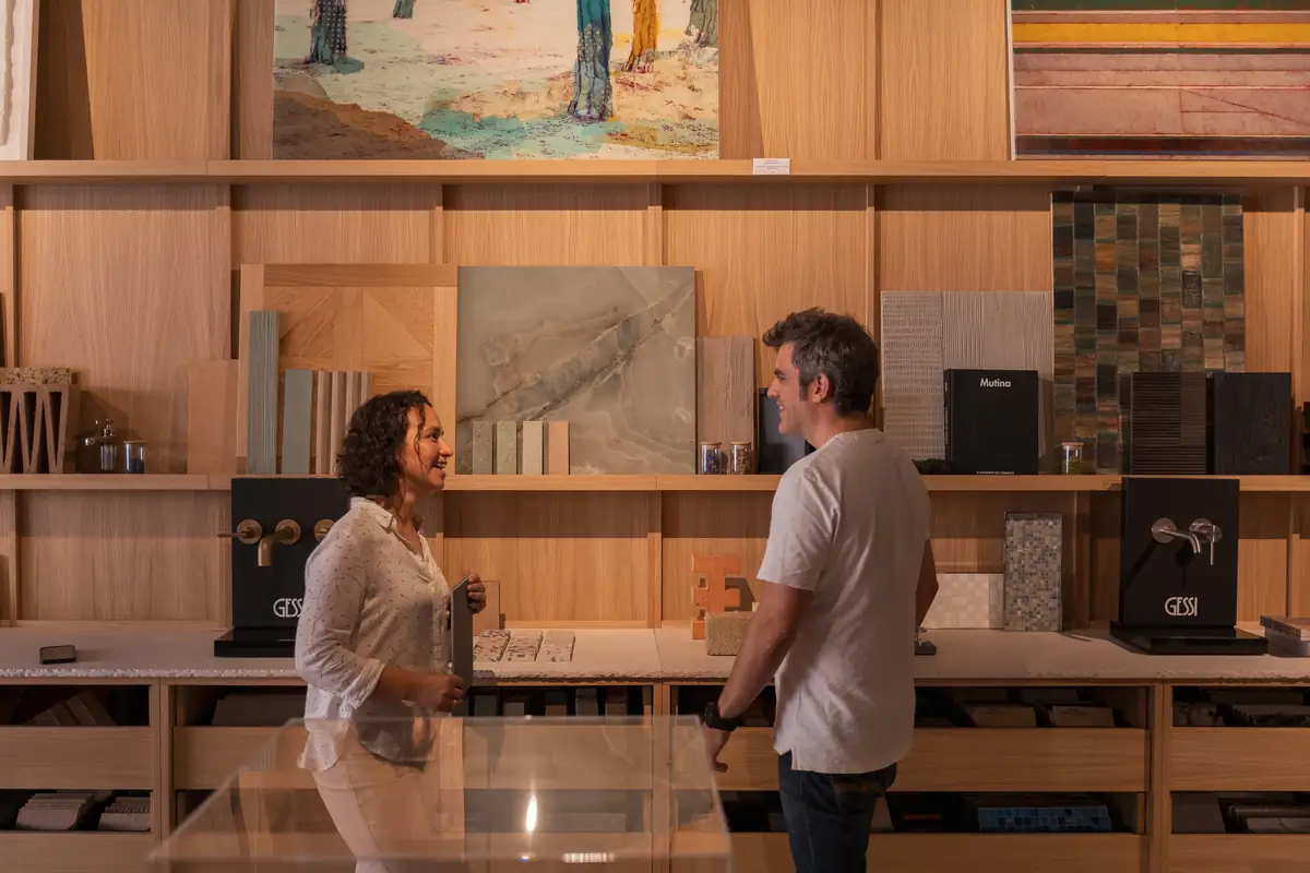Two people talk in front of the shelves of material samples