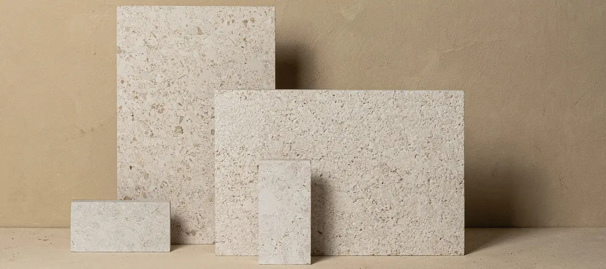Placas de caliza beige claro con sedimentos y fósiles visibles, de distintos tamaños.
