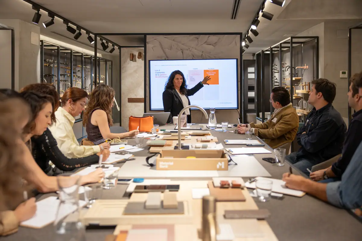 A speaker from Líderes para la Arquitectura points to the four-quadrant priority matrix in front of attendees seated at the sample table.