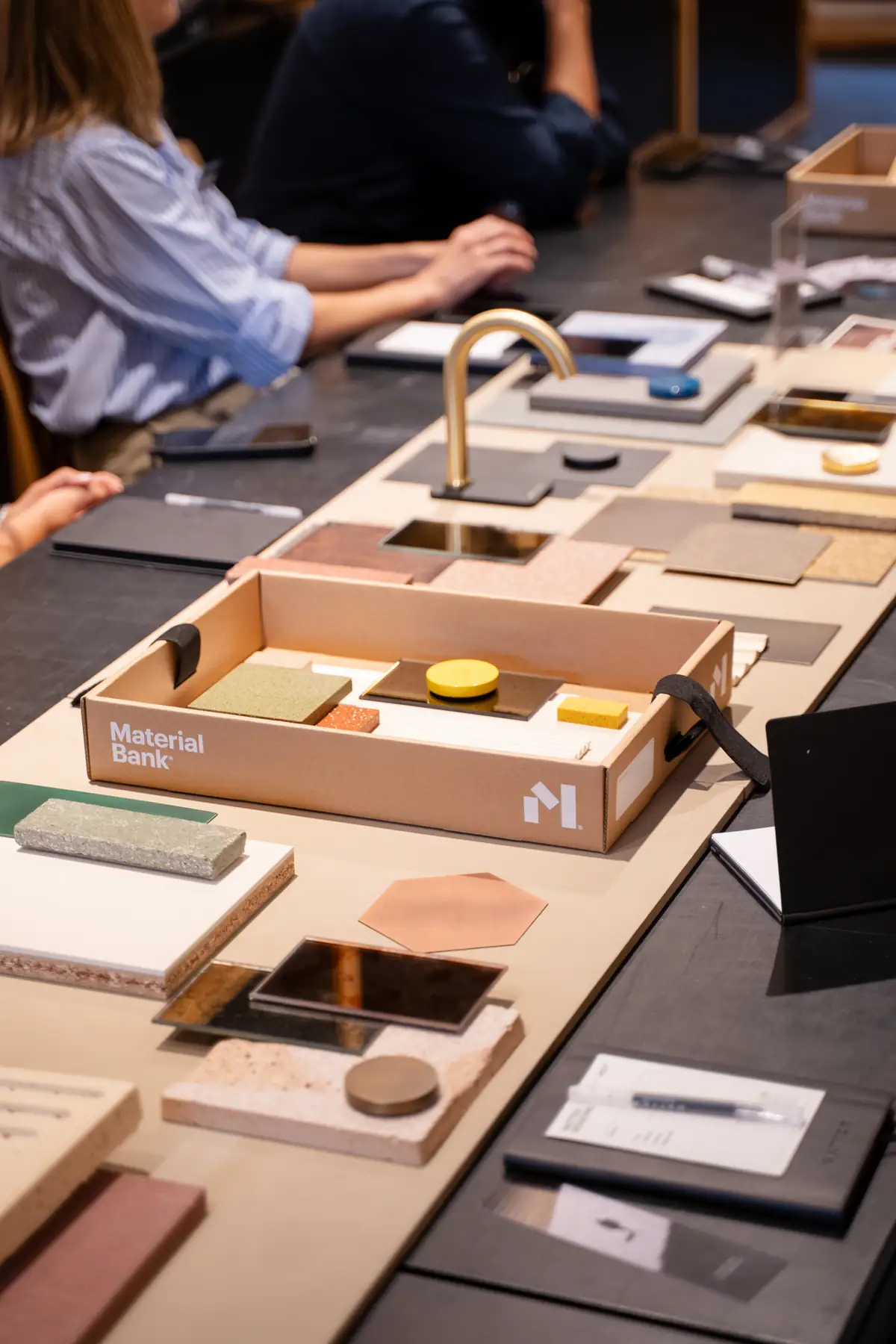 Session table with a Material Bank sample box, pieces of mirror, metal, stone and ceramic and a brass tap.