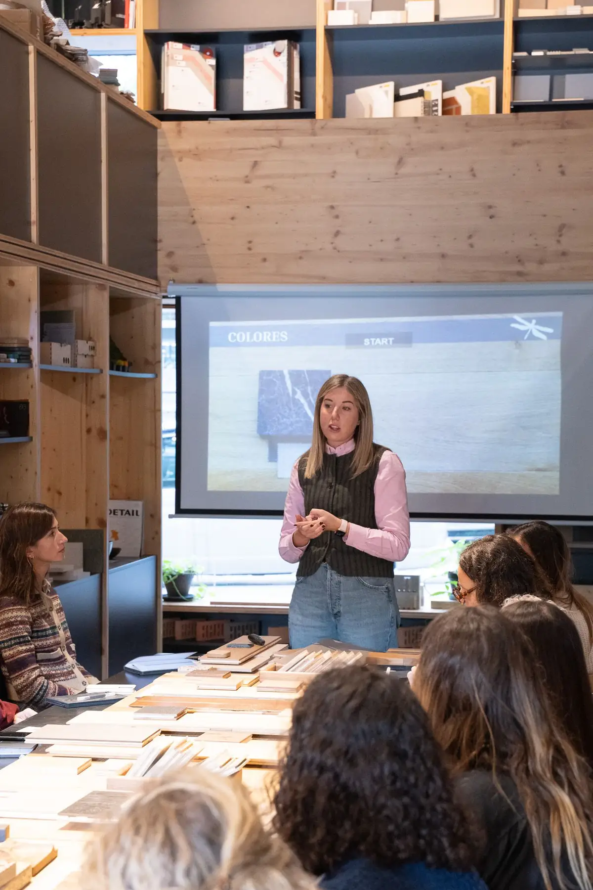 Andrea Pozzobon, of Mardegan Legno, speaks standing in front of a screen showing the word “Colores” and the dragonfly symbol.