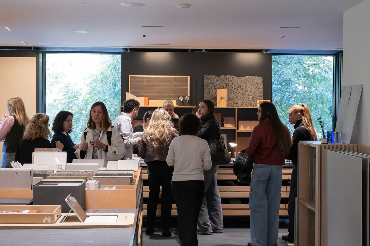 Attendees talking on their feet among tables and shelves with material samples.