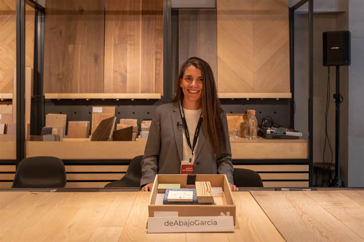 Begoña de Abajo standing behind her sample box labelled deAbajoGarcía, in front of wooden panels