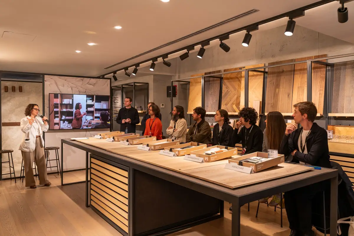 A speaker with a microphone addresses the architects seated around the Matter Madrid sample table