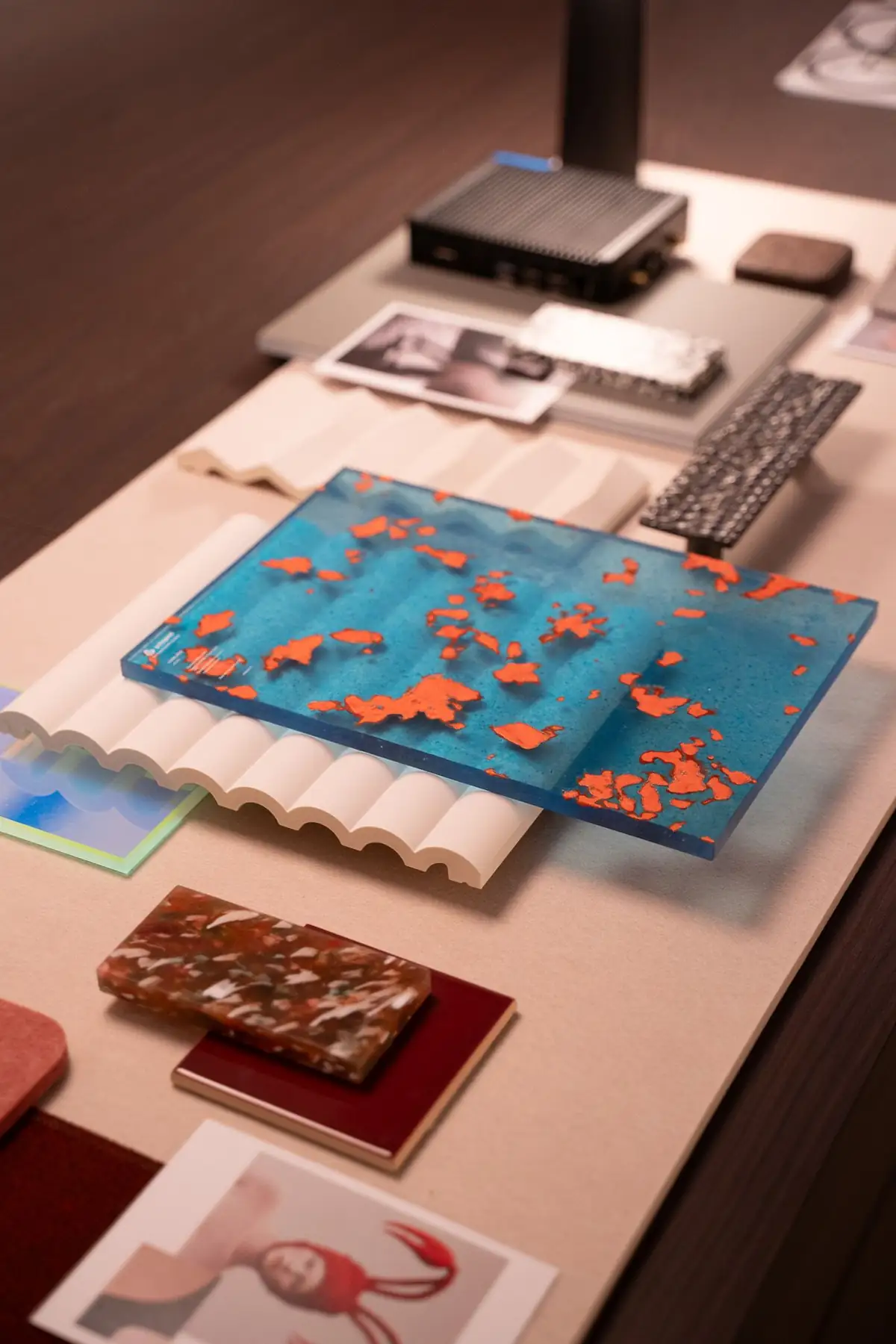Muestras de materiales de colores, entre ellas una placa azul con fragmentos naranjas, sobre una mesa