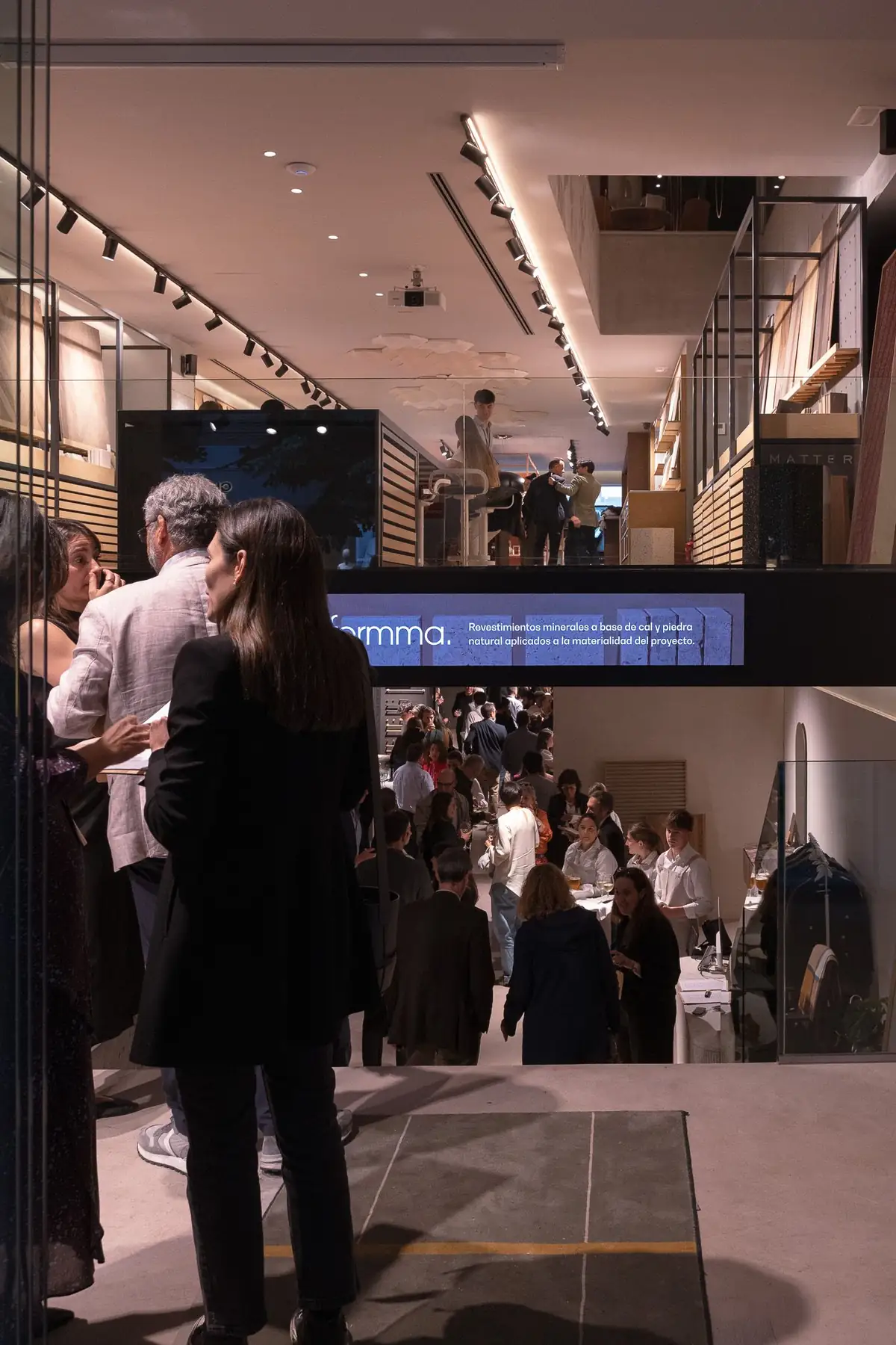 Interior del Meet Design Center a doble altura con visitantes y una pantalla de Formma