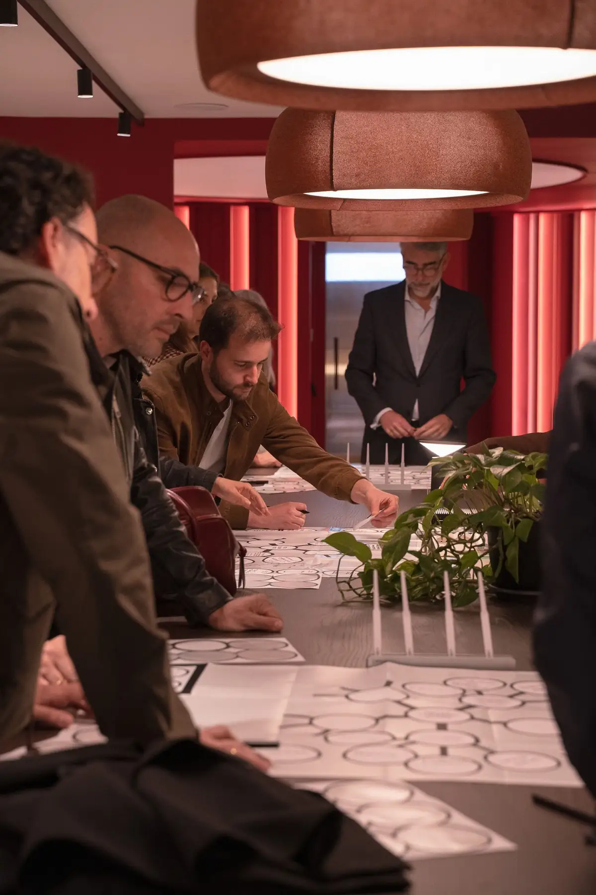 Asistentes inclinados sobre una mesa rellenando un mapa de Manual Thinking