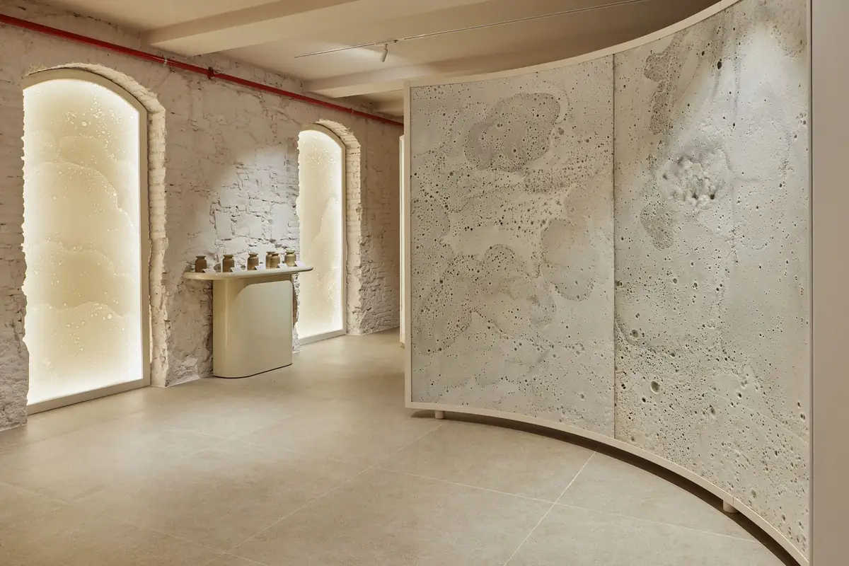 Arches in a whitewashed brick wall with panels lit from behind and a curved screen on the right