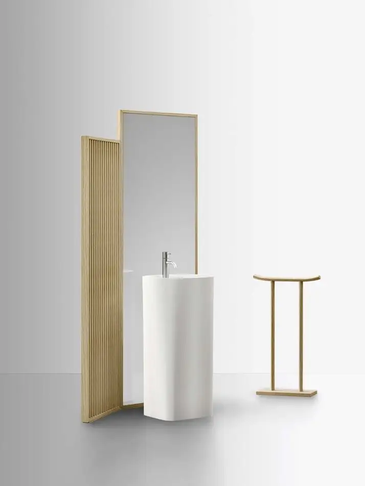 Lavabo de pie blanco de Cristalplant entre dos paneles de madera y espejo, con un toallero de madera, sobre fondo blanco.