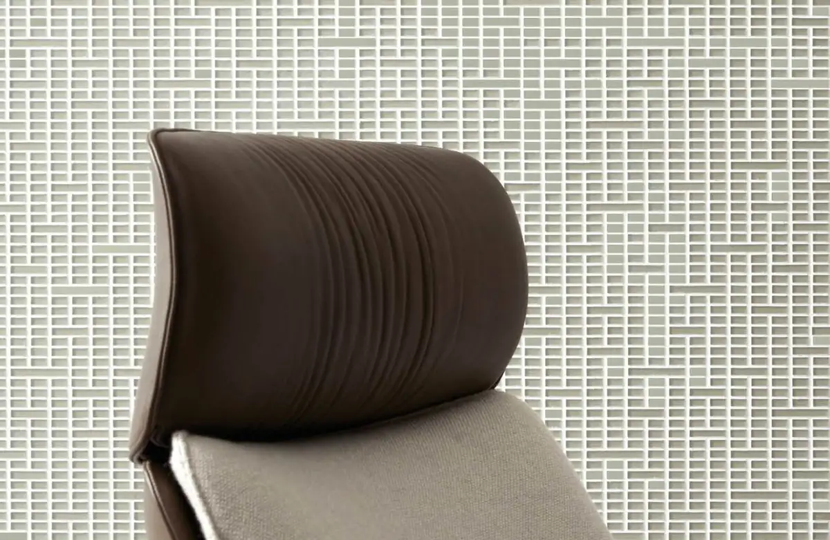 Detail of the pattern of light-toned Matter Uren behind the leather headrest of an armchair.