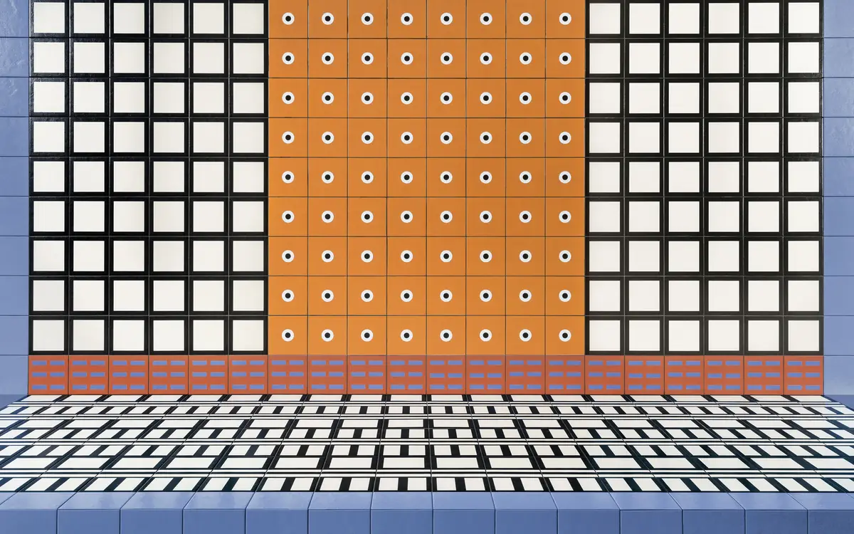 Tiled wall with white squares framed in black, a central orange panel with circles and light blue sides, above a striped floor
