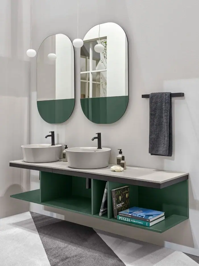 Pale ceramic countertop with two countertop basins on a green wall-hung open unit, with two oval mirrors