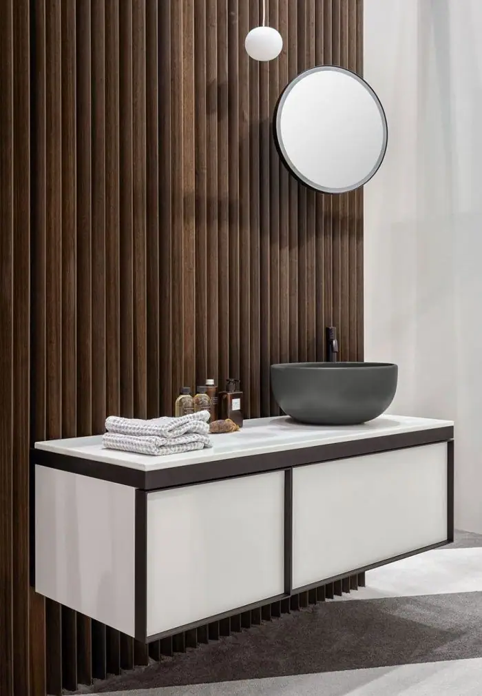 Dark grey countertop basin on a white countertop and white wall-hung two-drawer unit with a black frame, next to a wall of timber slats