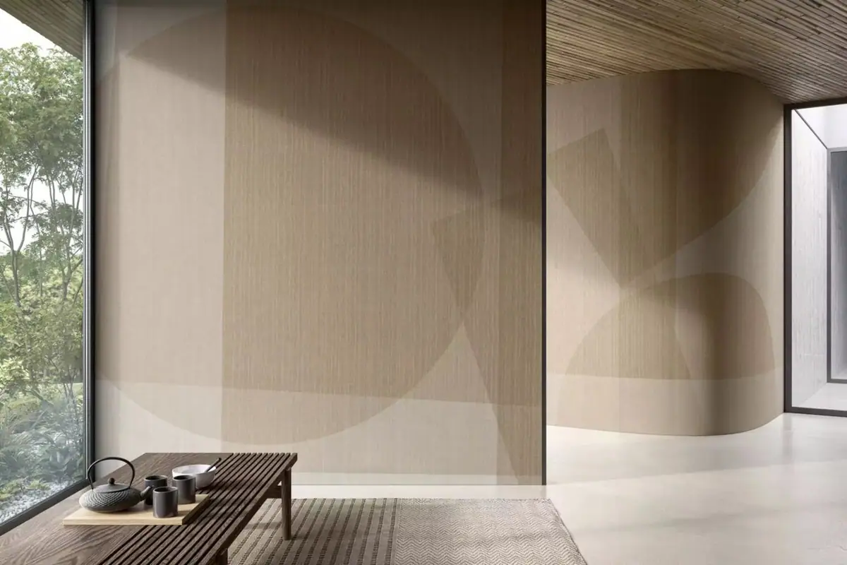 Room with one straight and one curved wall covered with overlapping circles and geometric planes in sand tones