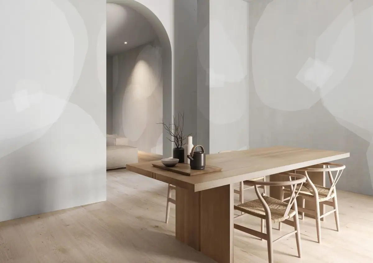 Dining room with a wooden table in front of white walls with large translucent grey circular forms