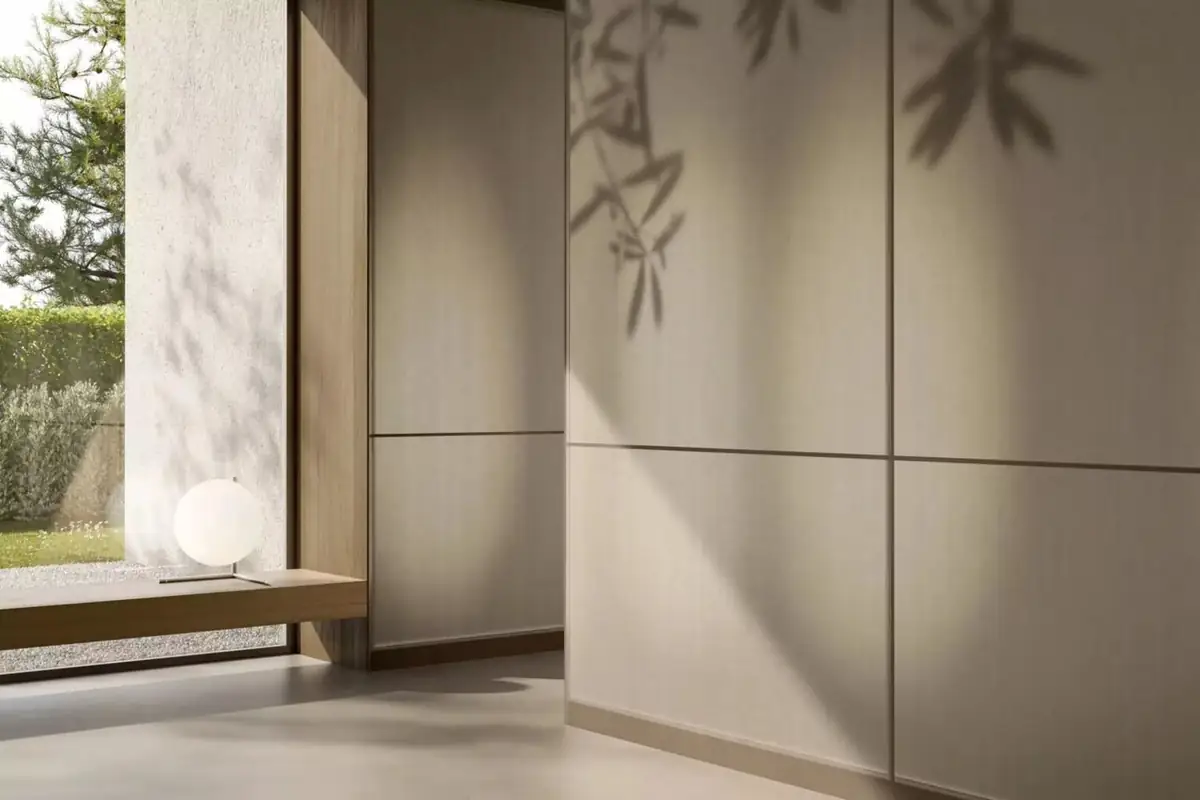 Interior with wallcovering panels in sand tones onto which the shadow of a shrub is cast