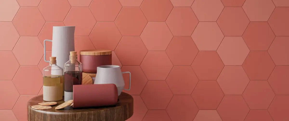 Pared revestida de hexágonos cerámicos en tonos coral con jarras, botellas y recipientes sobre una mesa redonda de madera