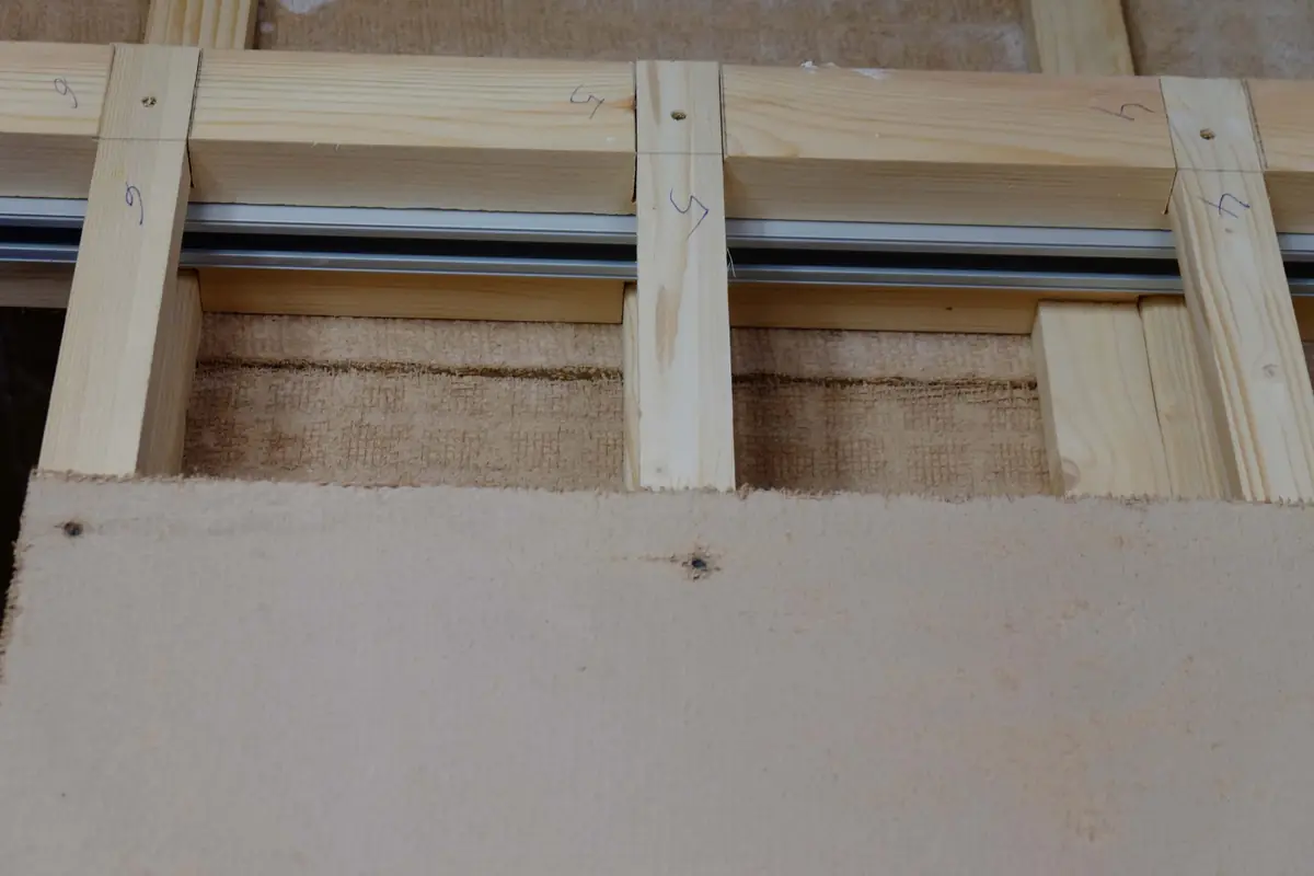 Placa de arcilla atornillada bajo una estructura de listones de madera en una obra